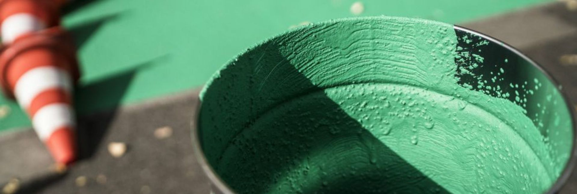 Farbeimer mit verkehrsgrüner Farbe für Beschichtung von Radweg