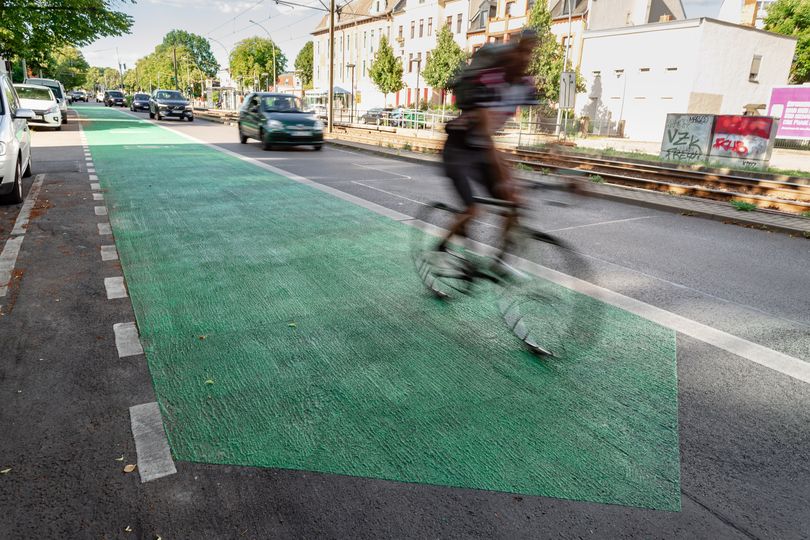 Grün beschichteter Radfahrstreifen in Pfeilform, auf dem ein Radfahrer fährt