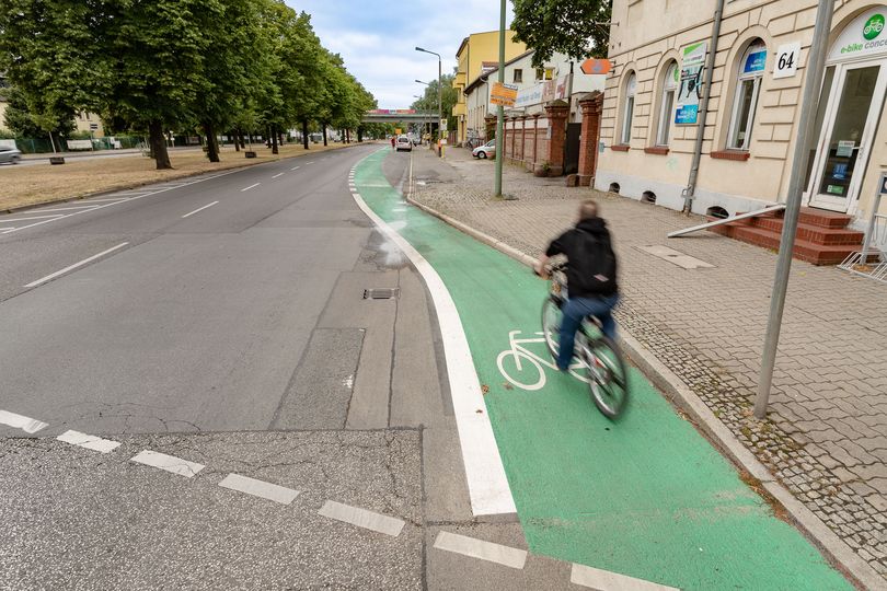 Fahrradfahrer fährt auf einem grün beschichteten Radfahrstreifen am Fahrbahnrand