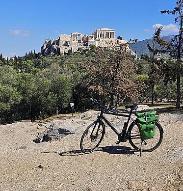 Fahrrad steht auf einem Berg, im Hintergrund die Akropolis