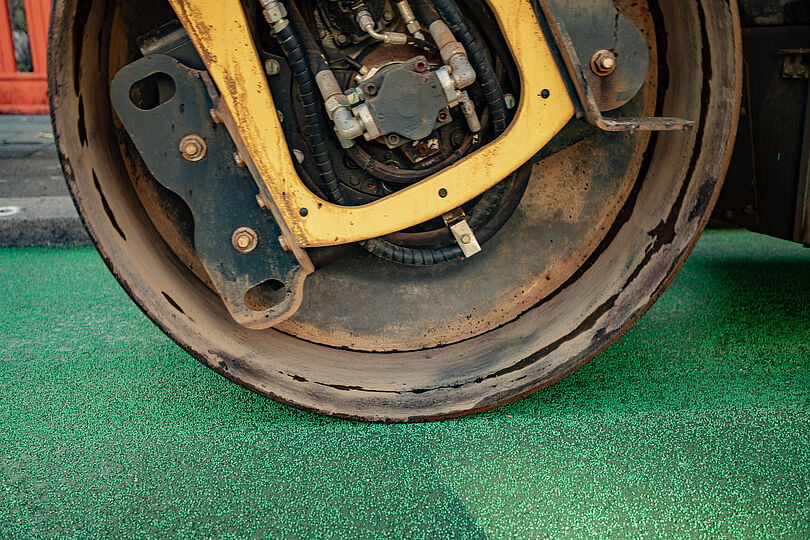 Eine Walze drückt den Split auf dem heißen Asphalt an.