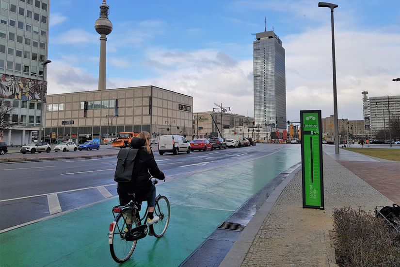 Fahrradfahrerin auf der Berliner Karl-Marx-Allee neben einem Fahrradbarometer