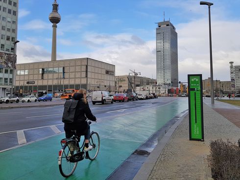 Fahrradfahrerin auf der Berliner Karl-Marx-Allee neben einem Fahrradbarometer