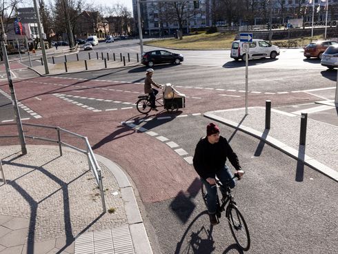 Fahrradfahrer fahren auf einem rotmarkierten Radweg auf einer Kreuzung