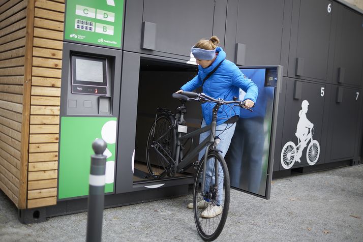 Eine Frau parkt ihr Fahrrad in einer Fahrradbox