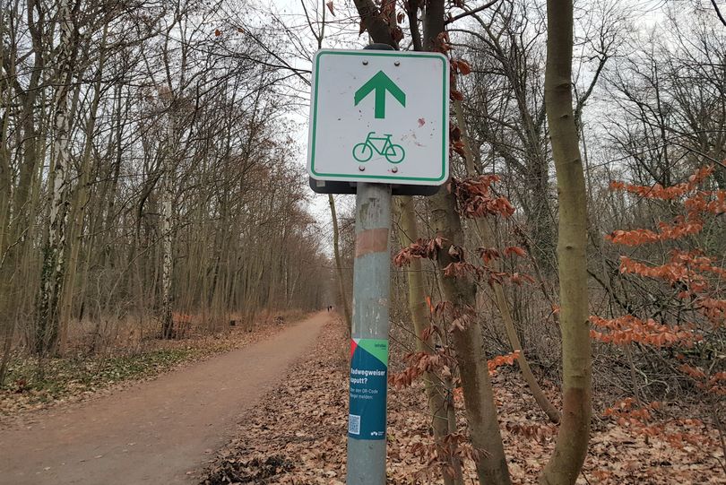 Radwegweiser mit Aufkleber, der auf das Mängelformular hinweist