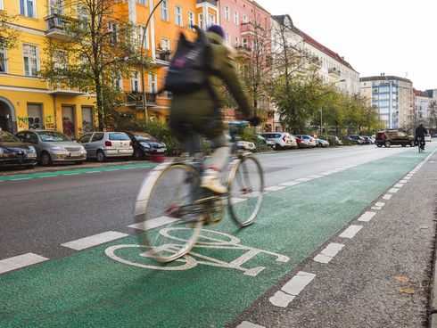 Fahrradfahrer fährt auf Straße mit grünem Radweg auf beiden Seiten
