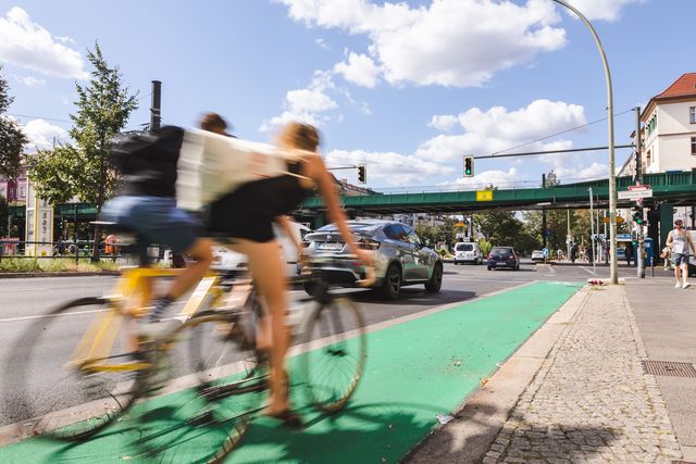 Radfahrende auf grün beschichtetem Radweg bei Sonnenschein Berlin