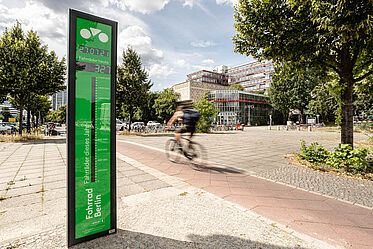 Fahrradbarometer im Vordergrund, dahinter fährt ein Radfahrer auf einem Fahrradweg