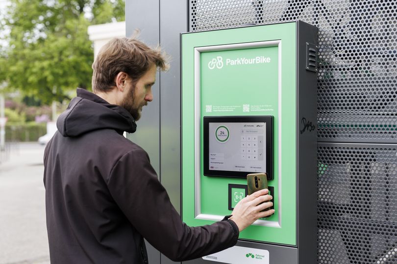 Ein Mann bedient ein Terminal an einer Sammelschließanlage für Fahrräder.