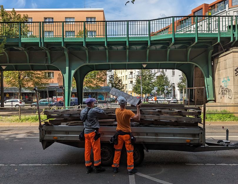 Bauarbeiter heben Holzlatten für den baumschutz von einem Anhänger auf der Schönhauser Allee