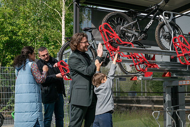 Mehrere Personen testen zusammen mit Kindern die Doppelstockparker der Fahrradabstellanlage