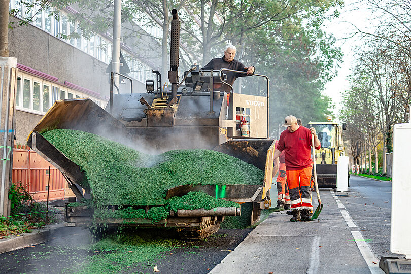 Der Asphalt wird gleichmäßig in der Breite des Radfahrstreifen aufgetragen.