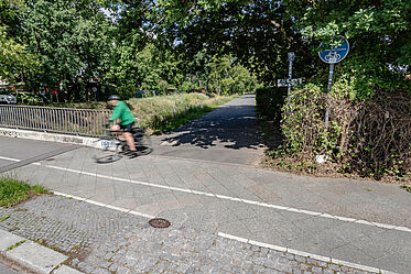 Einfahrt auf einen aspahltierten Weg für Rad- und Fußverkehr neben einem Kanal