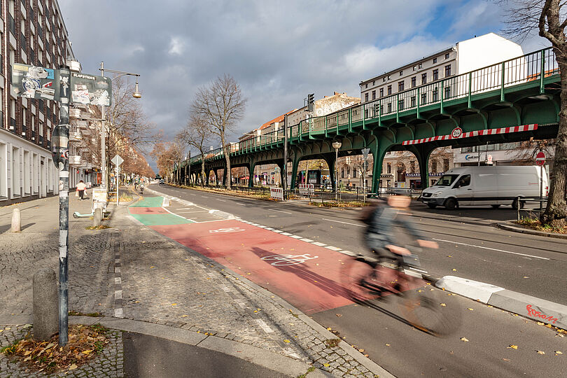 Radfahrer auf geschütztem Radfahrstreifen, im Hintergrund ist das Viadukt der U-Bahn zu sehen.