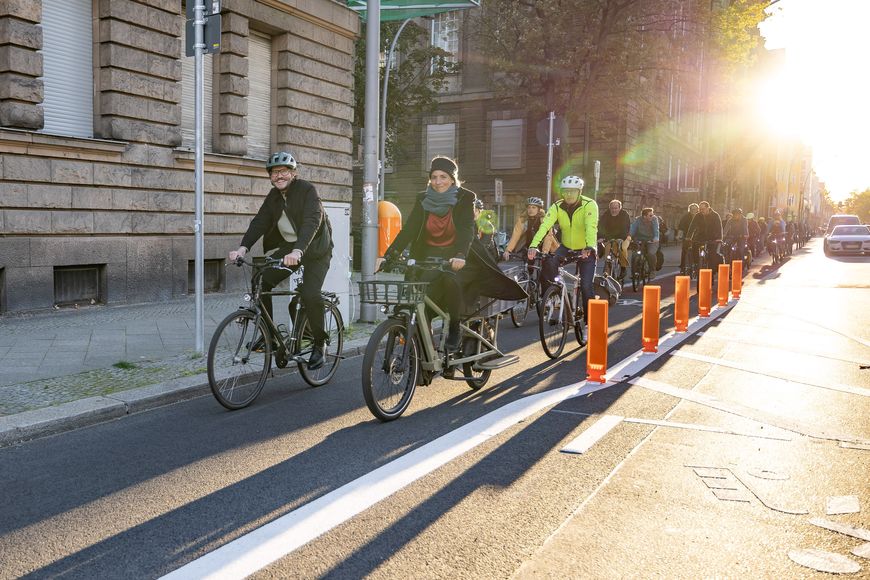 Mehrere Radfahrende fahren auf einem geschützten Radfahrstreifen in der Abendsonne.