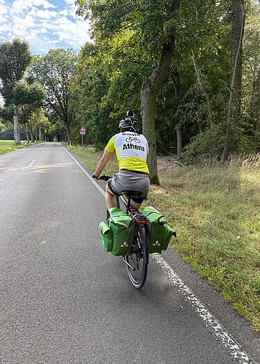 Radfahrer mit Gepäcktaschen fährt auf Landstraße