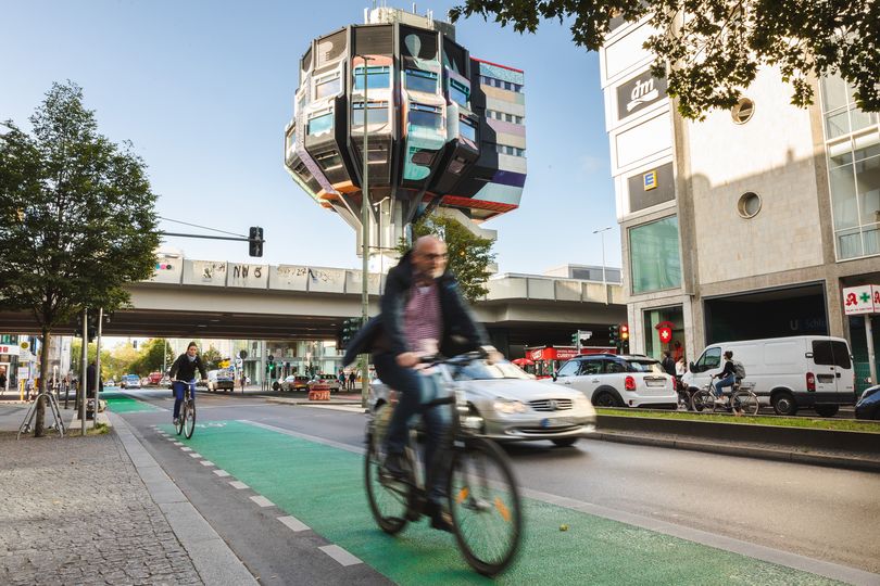 Ein Radfahrer fährt auf einem grünbeschichteten Radfahrstreifen, im Hintergrund ist der "Bierpinsel" zu sehen.