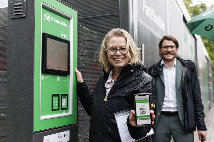 Ute Bonde steht am Terminal der gesicherten Abstellanlage und hält die ParkYourBike-App in die Kamera.