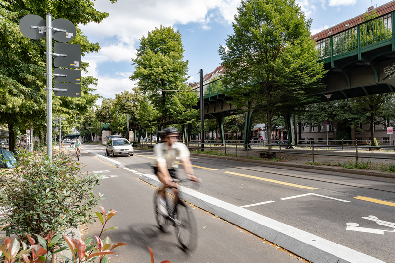 Radfahrer fährt auf einem mit Betonborden geschützten Radfahrstreifen, links von ihm sieht man eine markierte Ladezone für Lieferverkehr