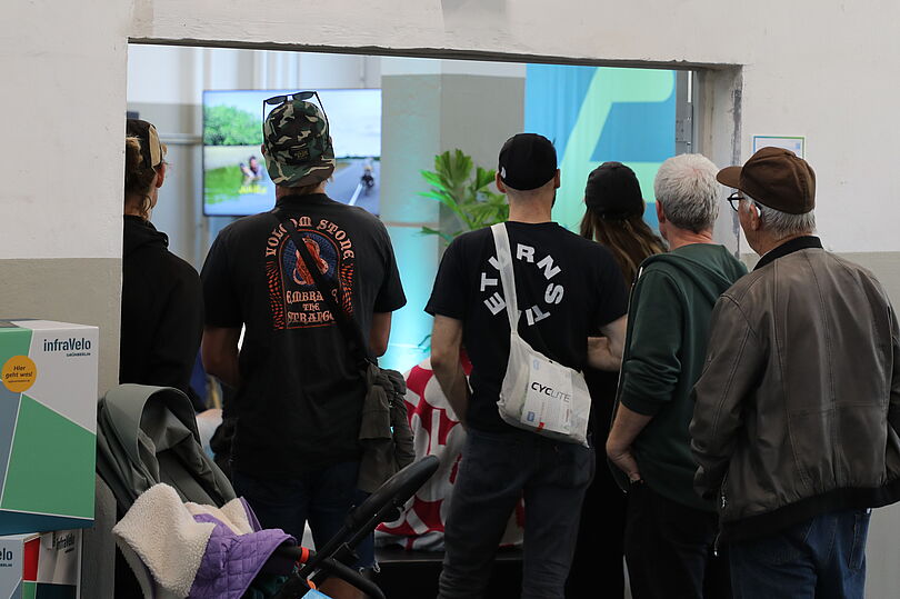 Mehrere Menschen sind von hinten zu sehen, die im Eingang zu einem Veranstaltungsraum stehen