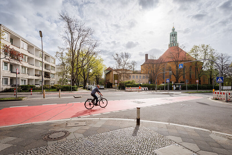 Radfahrer fährt auf einem breiten, rot markierten Radfahrstreifen auf einer Kreuzung