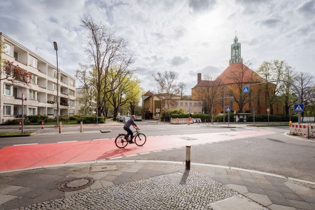 Radfahrer fährt auf einem breiten, rot markierten Radfahrstreifen auf einer Kreuzung