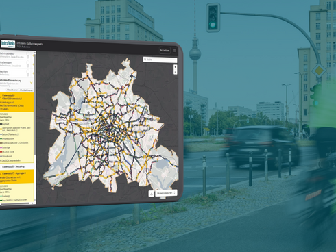 Tablet zeigt Karte von Berlin mit Radnetz, im Hintergrund Fahrradweg mit Radfahrenden in Mitte
