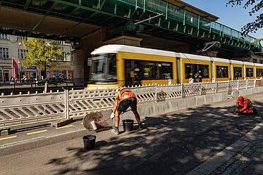 Bauarbeiten an einem Radfahrstreifen, Einbau von Beton-Borden. Im Hintergrund fährt eine Straßenbahn vorbei.