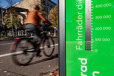 Fahrradbarometer im Vordergrund, dahinter fährt ein Radfahrer auf einem Fahrradweg