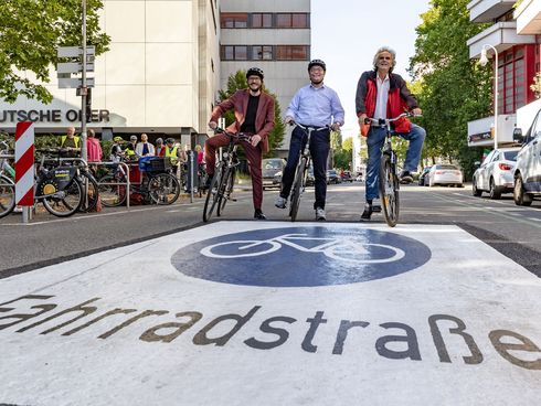 Michael Fugel, Arne Herz und Olier Schruoffeneger mit Fahrrädern auf einer Straße mit Fahrradstraßen-Piktogramm
