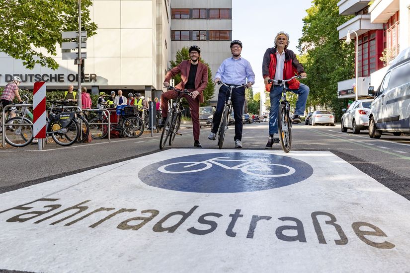 Michael Fugel, Arne Herz und Olier Schruoffeneger mit Fahrrädern auf einer Straße mit Fahrradstraßen-Piktogramm