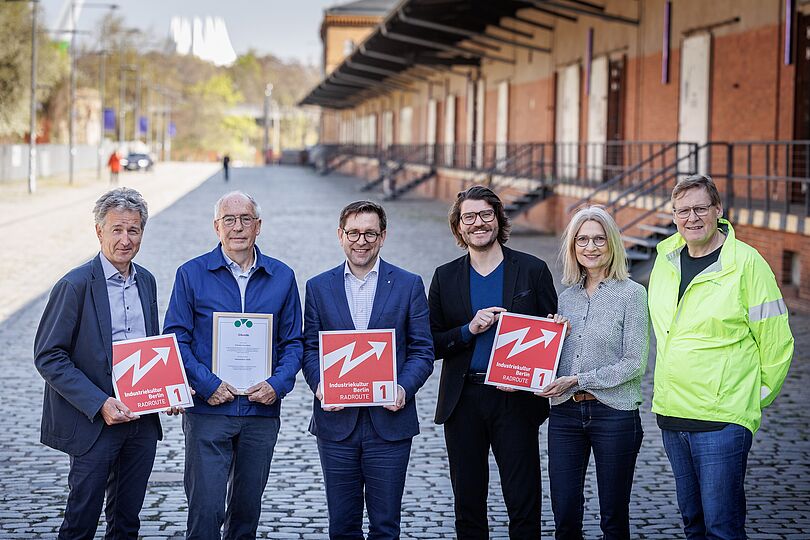Gruppenfoto von sechs Personen, die zwei Schilder der Radroute hochhalten