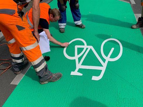 Bauarbeiter tragen Fahrradicon auf grünen Radfahrstreifen auf in Berlin 