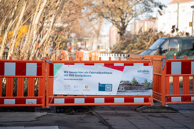 Baustellenzaun in orange und rot. Bauzaunbanner mit Informationen zum Bau des Fahrradparkhauses Schöneweide