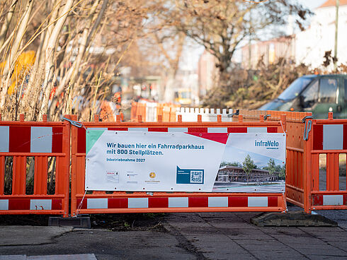 Baustellenzaun in orange und rot. Bauzaunbanner mit Informationen zum Bau des Fahrradparkhauses Schöneweide