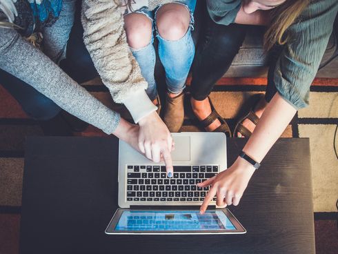 Mehrere Personen schauen zusammen auf einen Laptop-Bildschirm