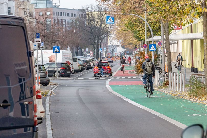 Radfahrer fährt auf einem grün und rot beschichteten Radfahrstreifen am rechten Fahrbahnrand.
