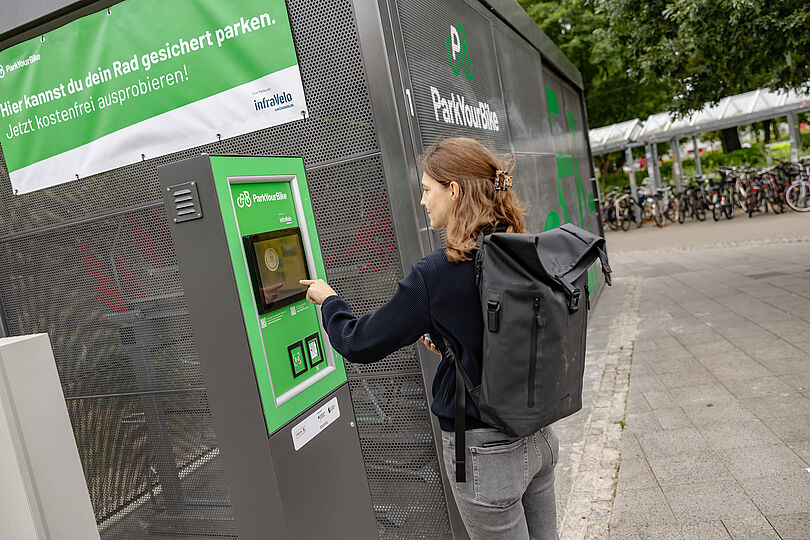 Eine Frau bedient das Terminal einer gesicherten Fahrradabstellanlage.