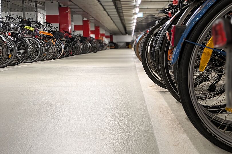 Blick den den gang eines Fahrradparkhauses mit abgestellten Fahrrädern links und rechts