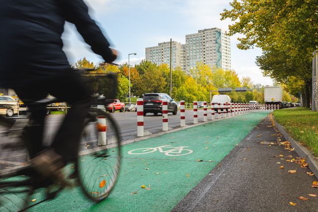 Radfahrer fährt auf einem grünmarkierten und mit Pollern geschützten Radfahrstreifen.