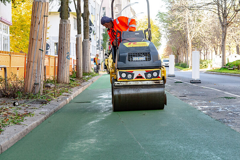 Walzen verdichten die heiße Asphaltschicht, um eine ebene und gleiche Oberfläche zu erzeugen.