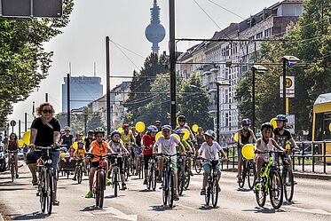 Mehrere Kinder fahren Fahrrad nebeneinander auf einer Straße in Berlin