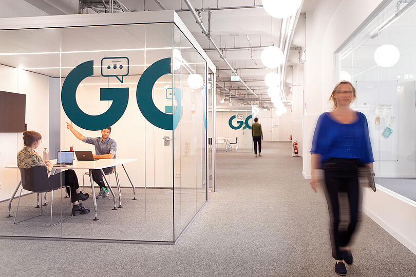 Blick auf einen Flur mit Büroräumen und einem gläsernen Besprechungsraum.