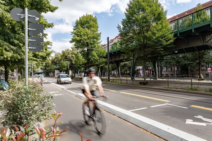 Fahrradfahrer fährt über Radfahrstreifen mit Protektionselementen