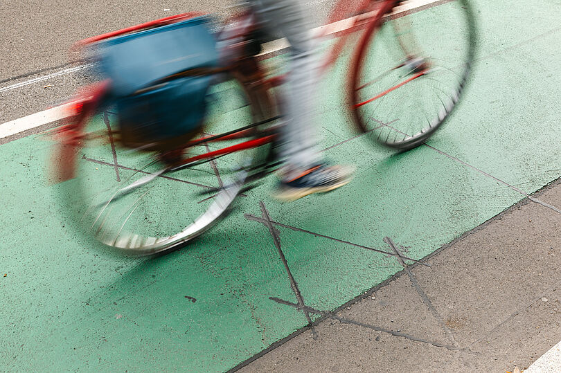 Fahrrad fährt auf einem grünmarkierten Radfahrstreifen. Einschnitte im Asphalt markieren den Standort der Zählstelle.