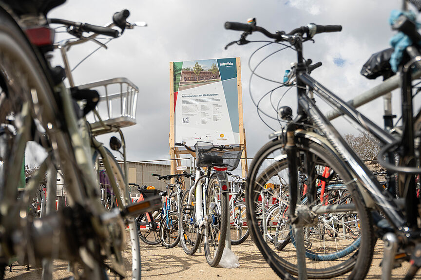 Baustellenschild für Fahrradparkhaus, im Vordergrund abgestelle Fahrräder