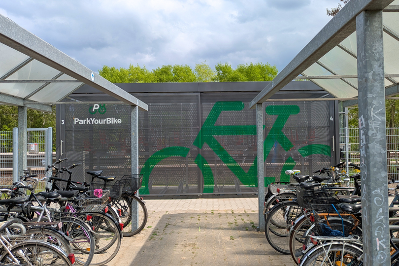 Sammelschließanlage für Fahrräder am S-Bahnhof, im Vorderund abgestellte Fahrräder an Bügeln