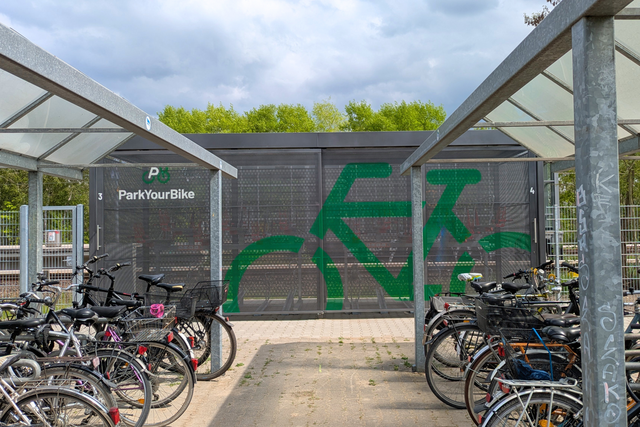 Sammelschließanlage für Fahrräder am S-Bahnhof, im Vorderund abgestellte Fahrräder an Bügeln