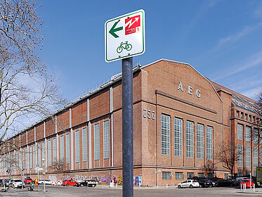 Radwegweiser vor einem Backsteingebäude